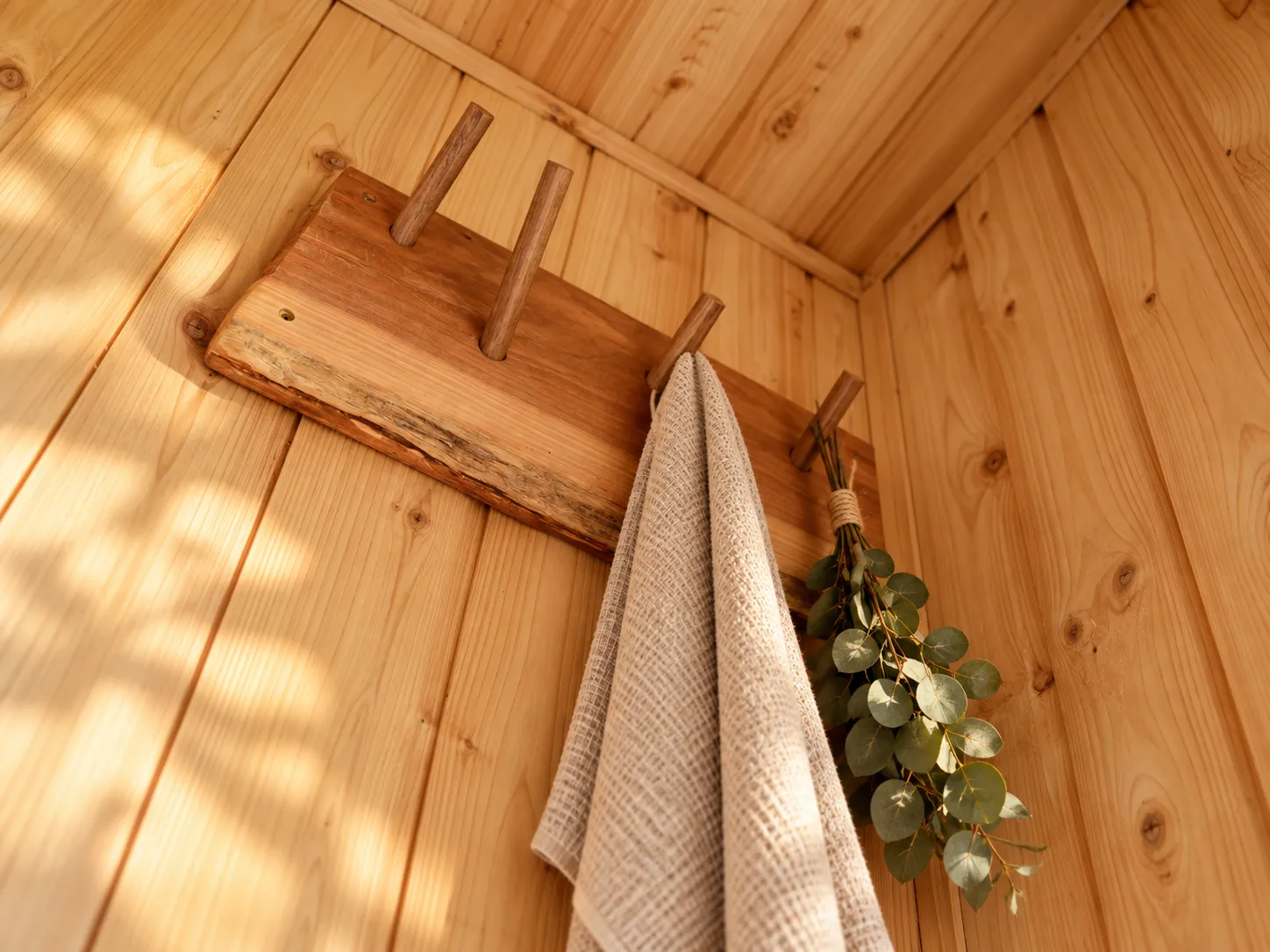 Natural timber, a linen towel and a wooden peg rail inside a sauna